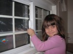 Young girl applying air sealing film to a window